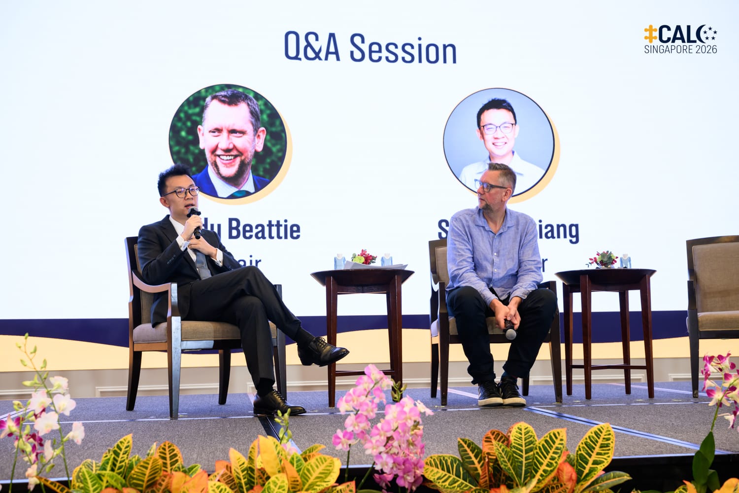 Speaker Seow Zhixiang speaks during a Q&A session at the Conference at The Fullerton Hotel Singapore, with chair Andy Beattie seated beside him on stage.